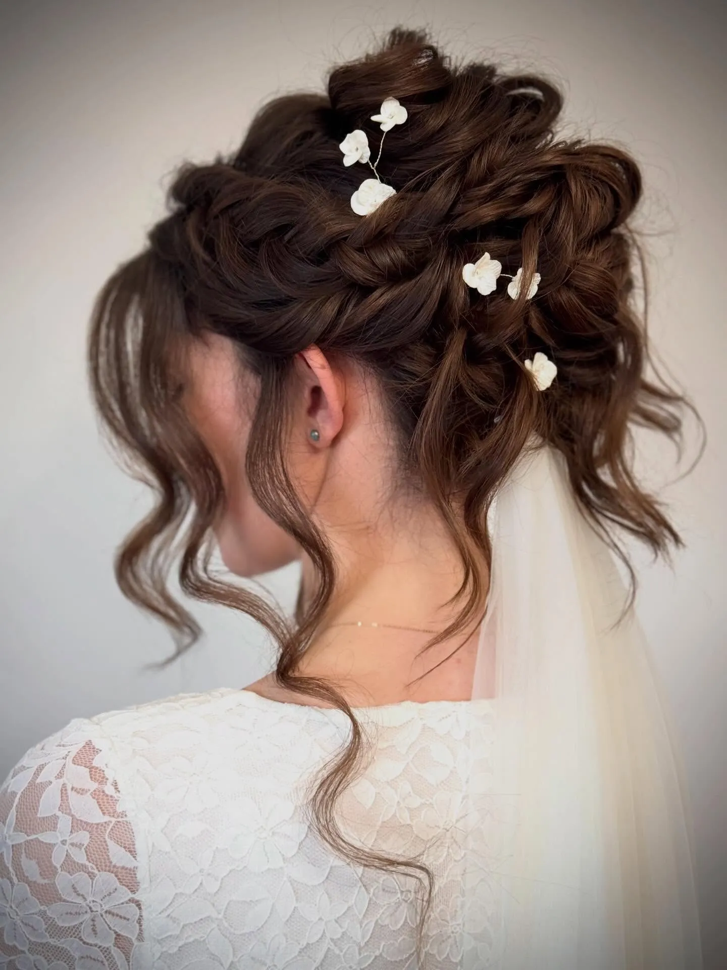 Loose bridal updo with white flower pins and a veil
