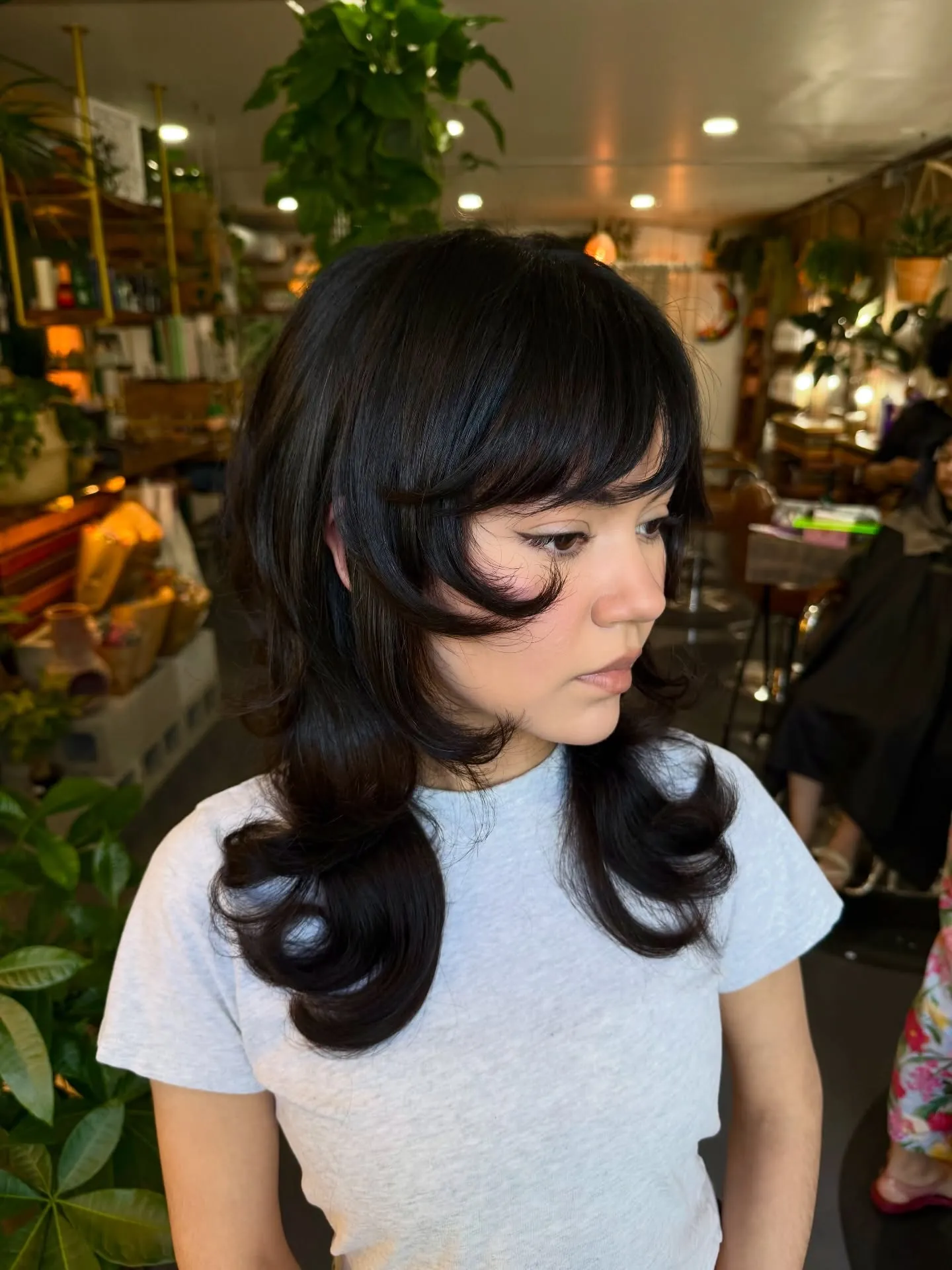 Dark layered haircut with bangs and strongly curled-out ends