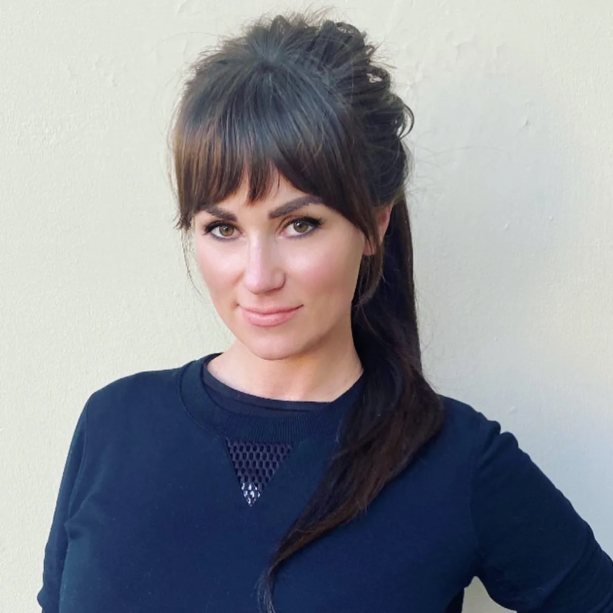 Ponytail hairstyle with full brow-skimming Birkin bangs