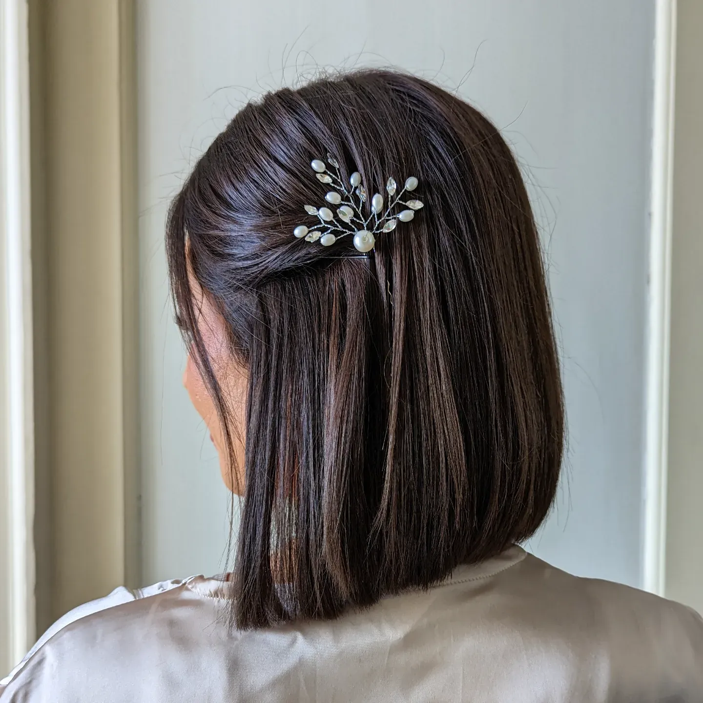 Straight dark bob with a pearl branch clip and half-up twist