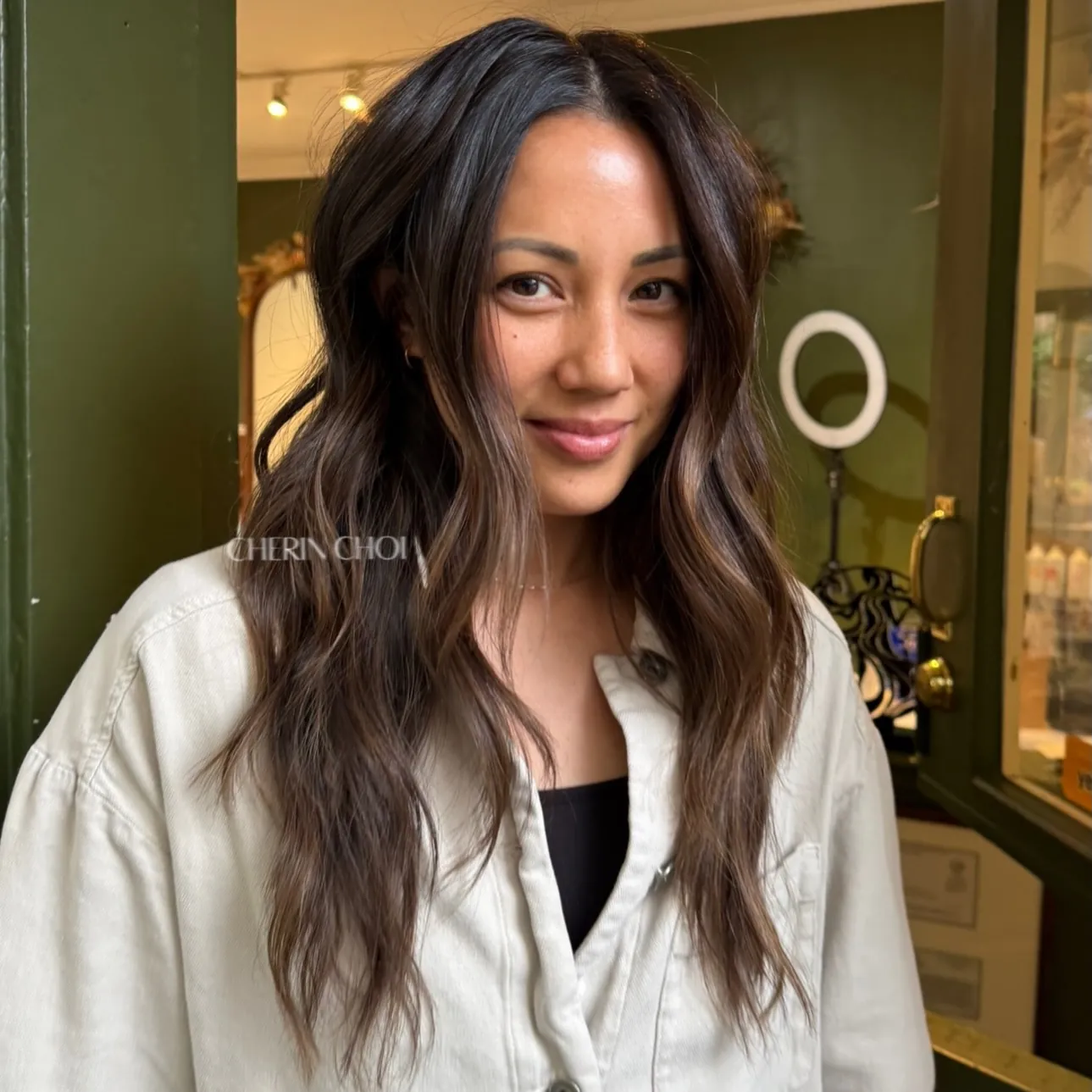 Long charcoal brunette hair with loose textured waves and subtle dimension