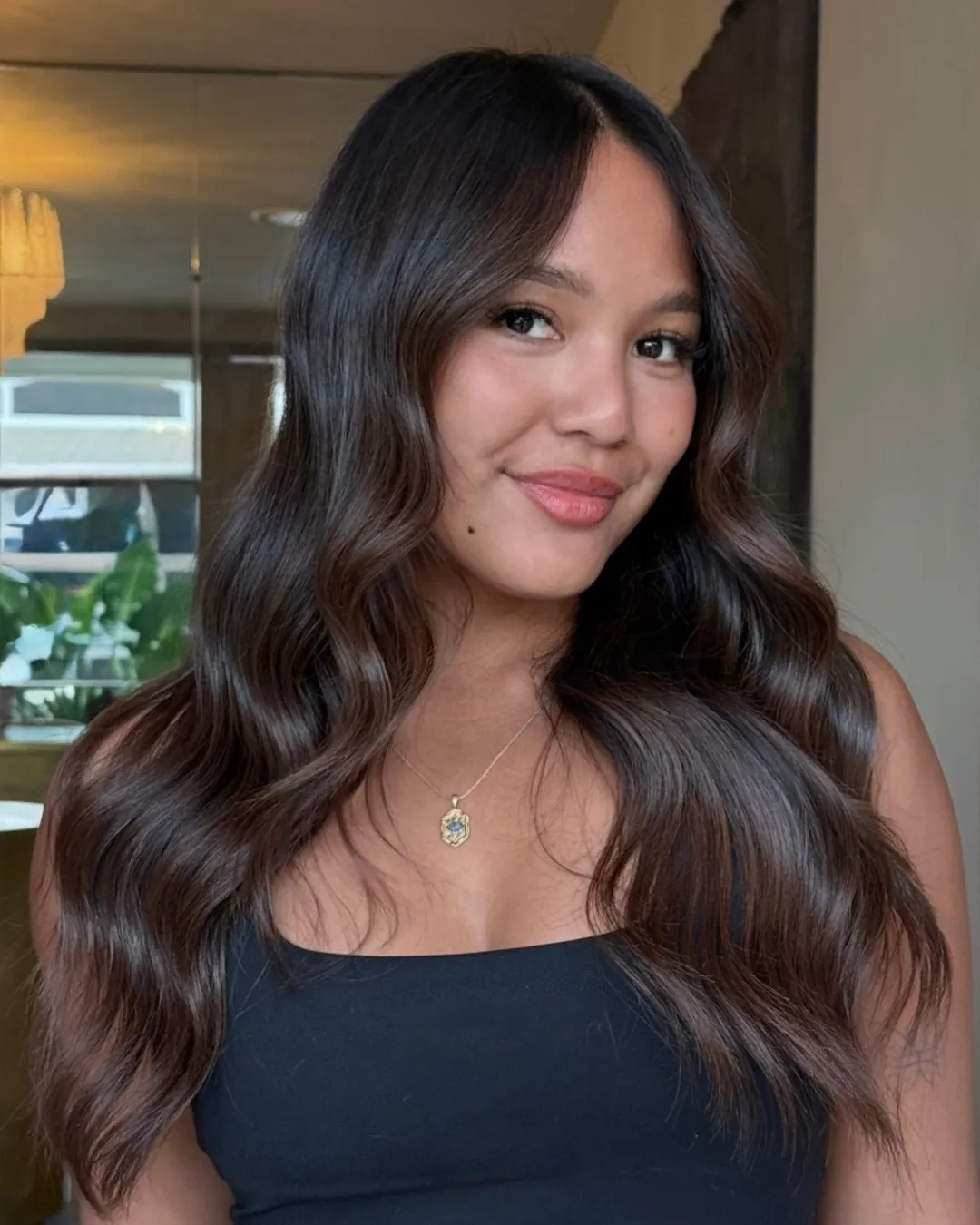 Long polished charcoal brunette hair styled in uniform glossy waves