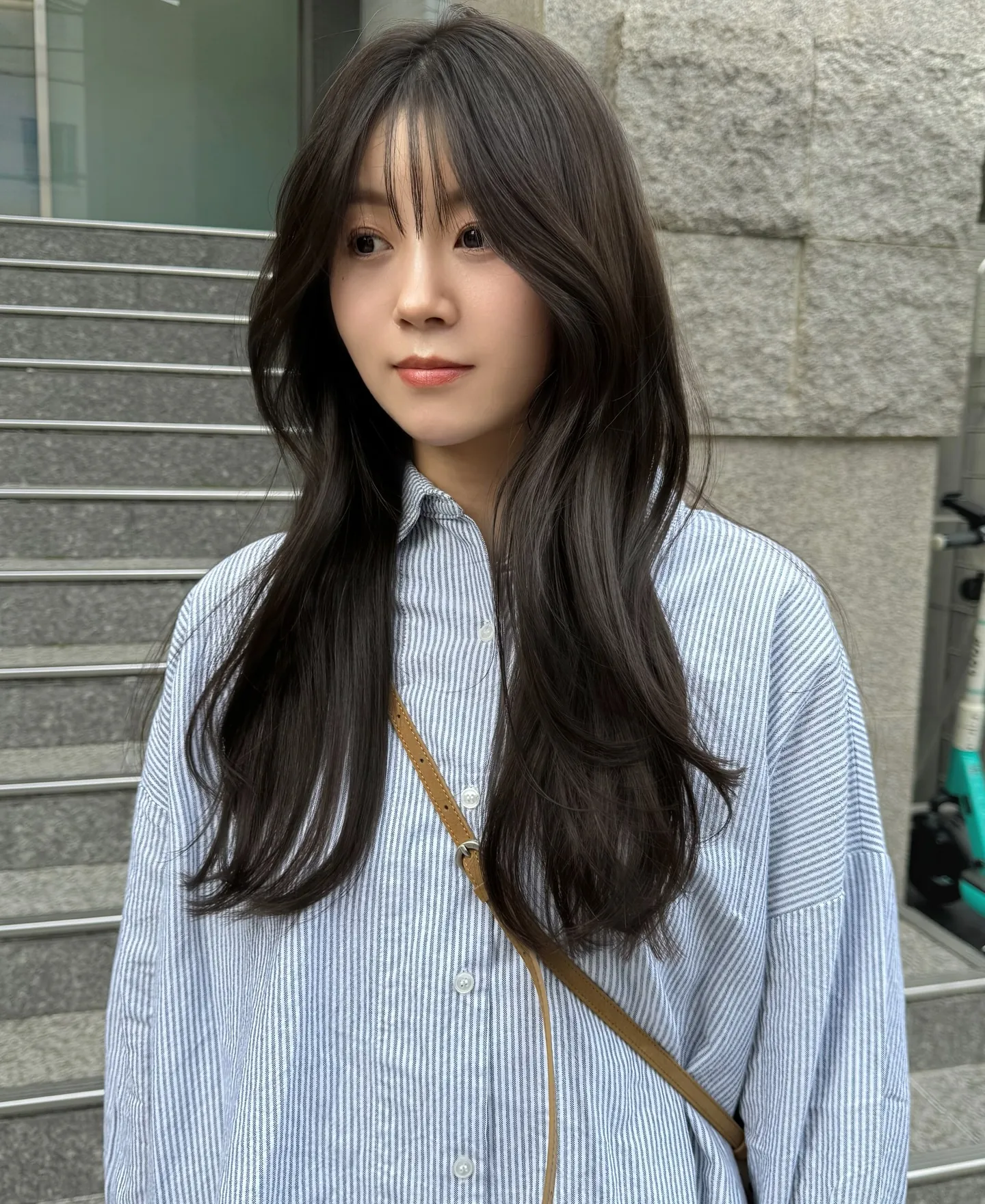 Long charcoal brunette hair with wispy bangs and sleek layered lengths