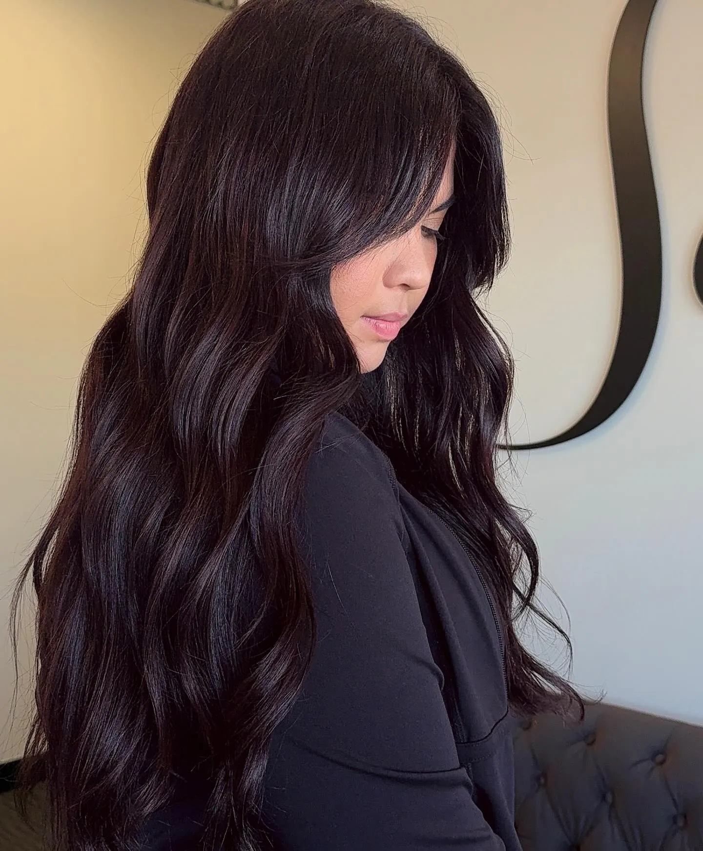 Long deep charcoal brunette hair styled in glossy loose waves
