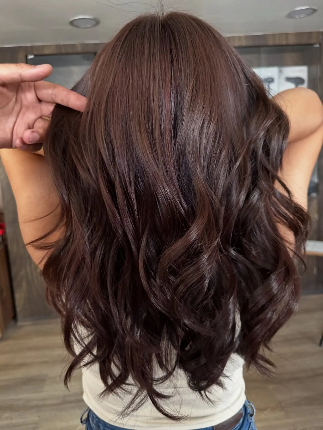 Charcoal brunette hair styled in polished loose curls from the back