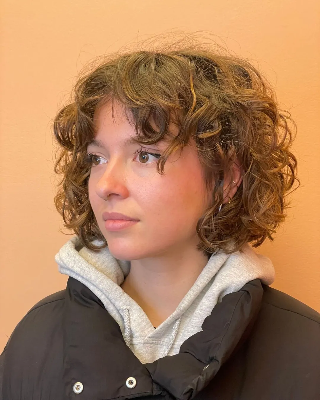 Rounded curly bixie with soft fringe and cheek-length curls