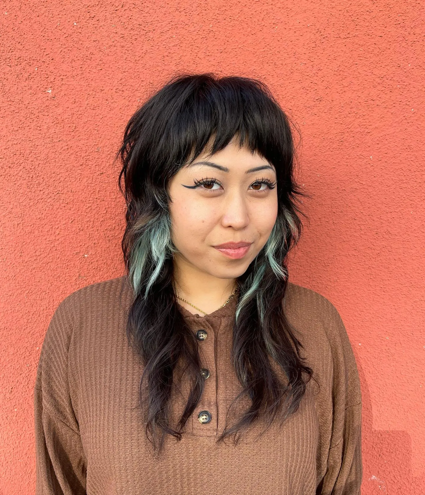 Dark mullet shag with teal face-framing pieces and short fringe