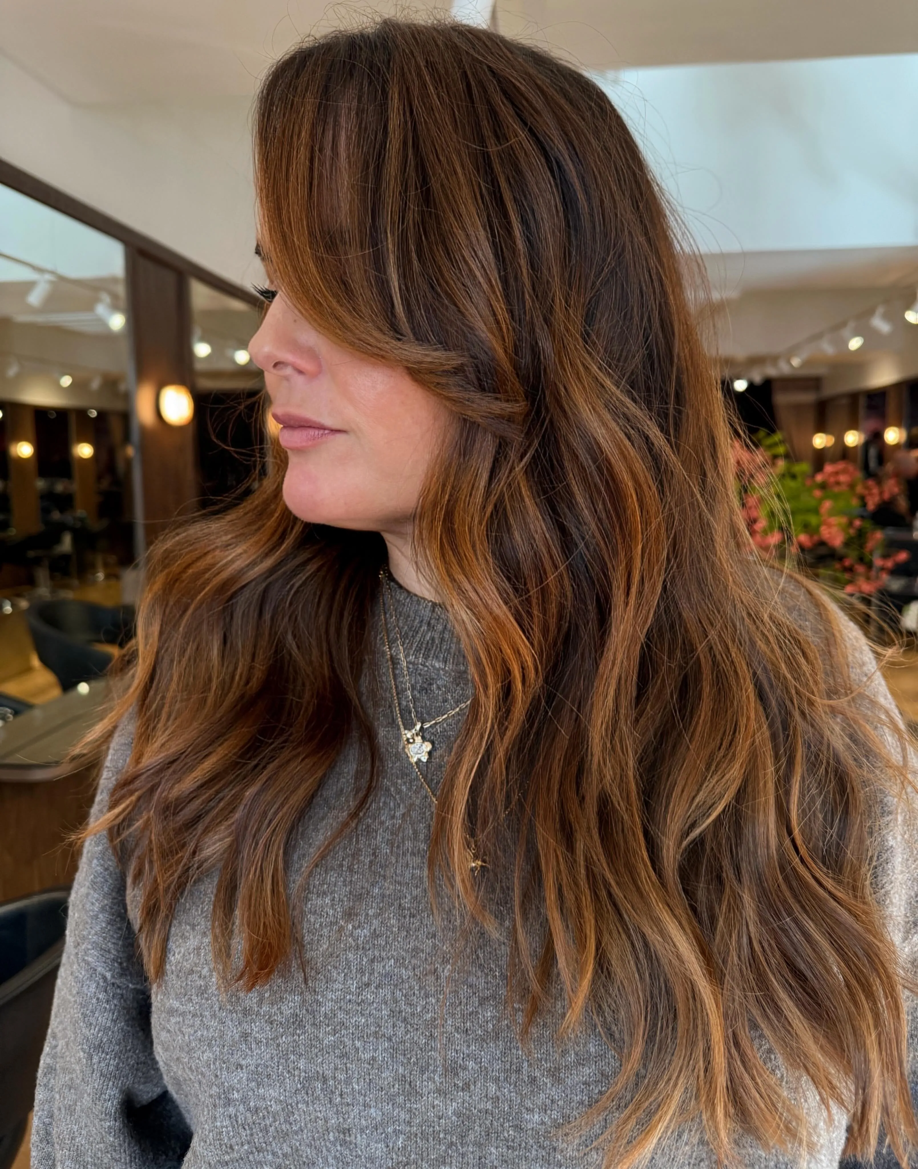 Long brunette layers with curtain bangs and soft waves