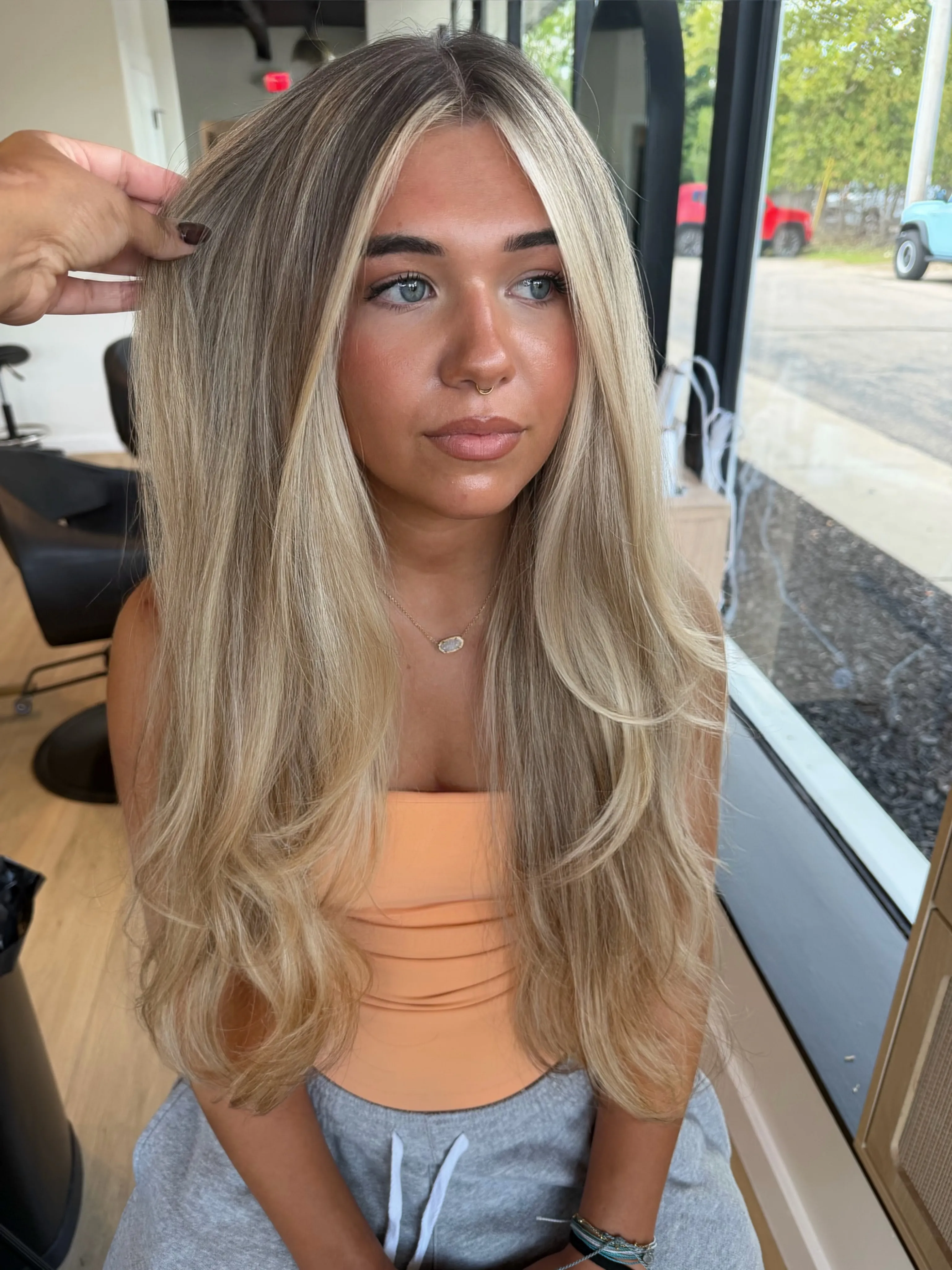 Long sleek blonde layers with center part and cool root depth