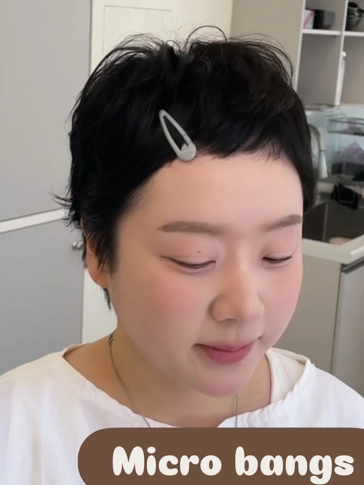 Short black pixie with micro bangs and a small hair clip