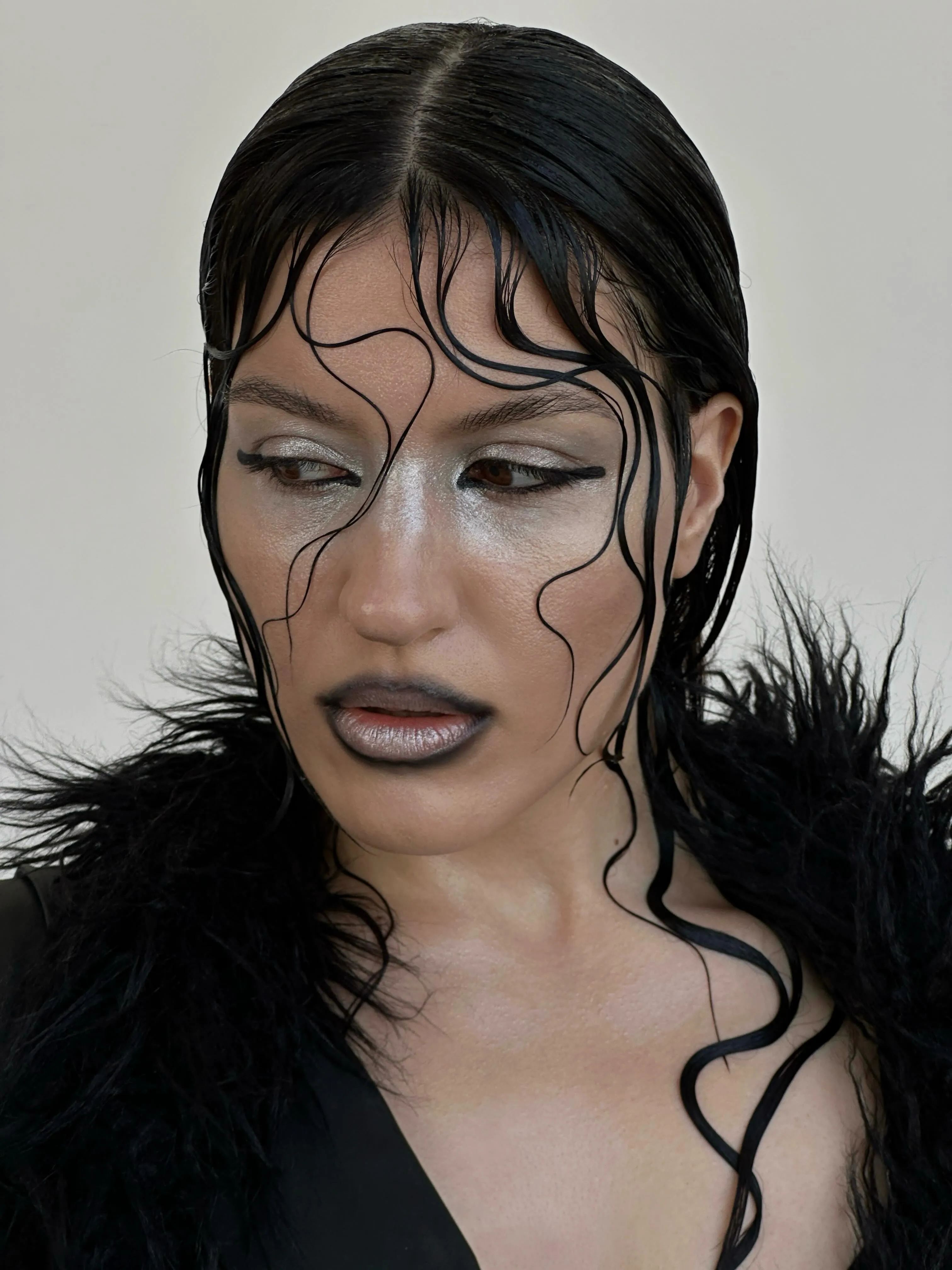 Slick black hair with wet-look sculpted tendrils across the face