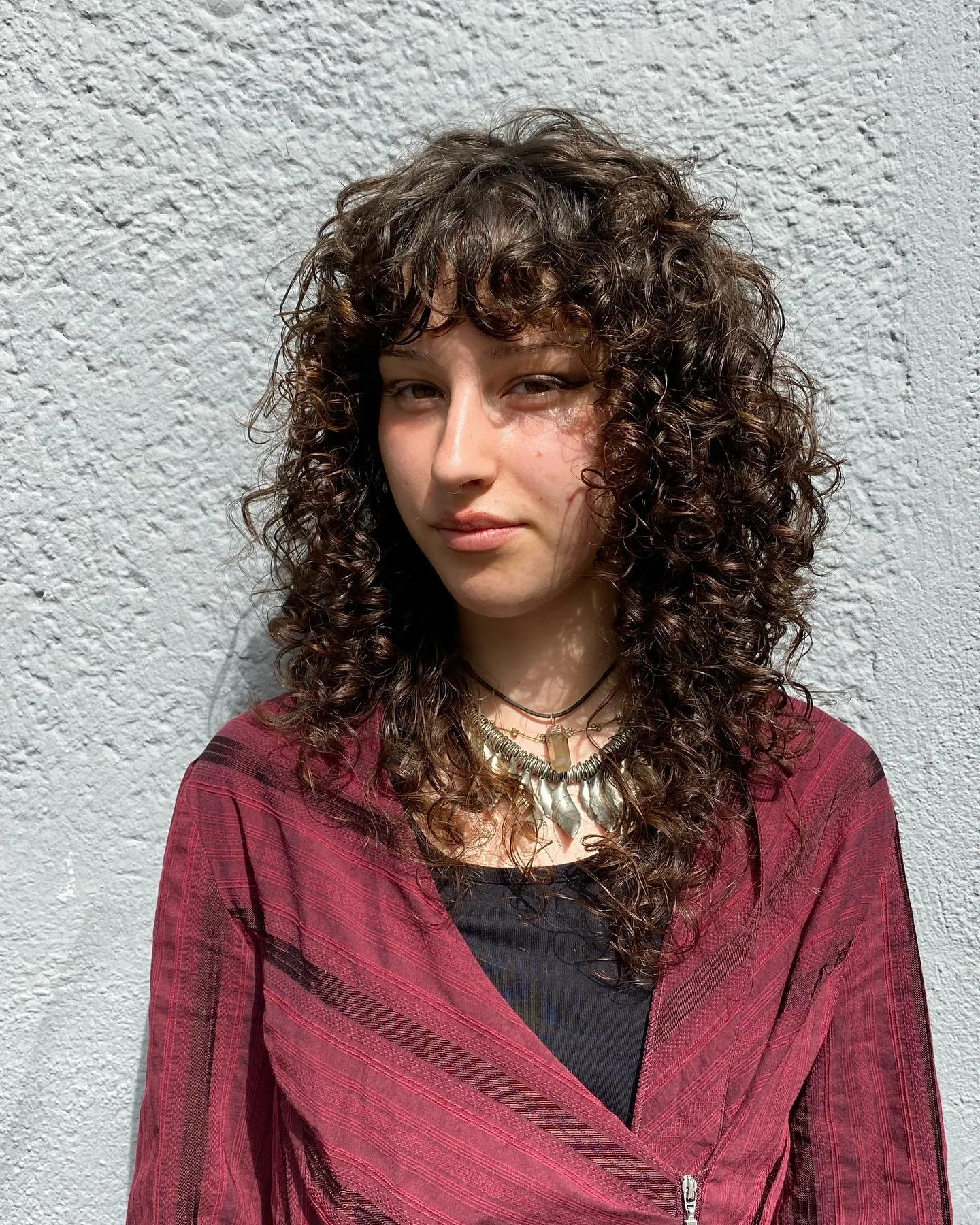 Tight dark curls with short fringe and layered length