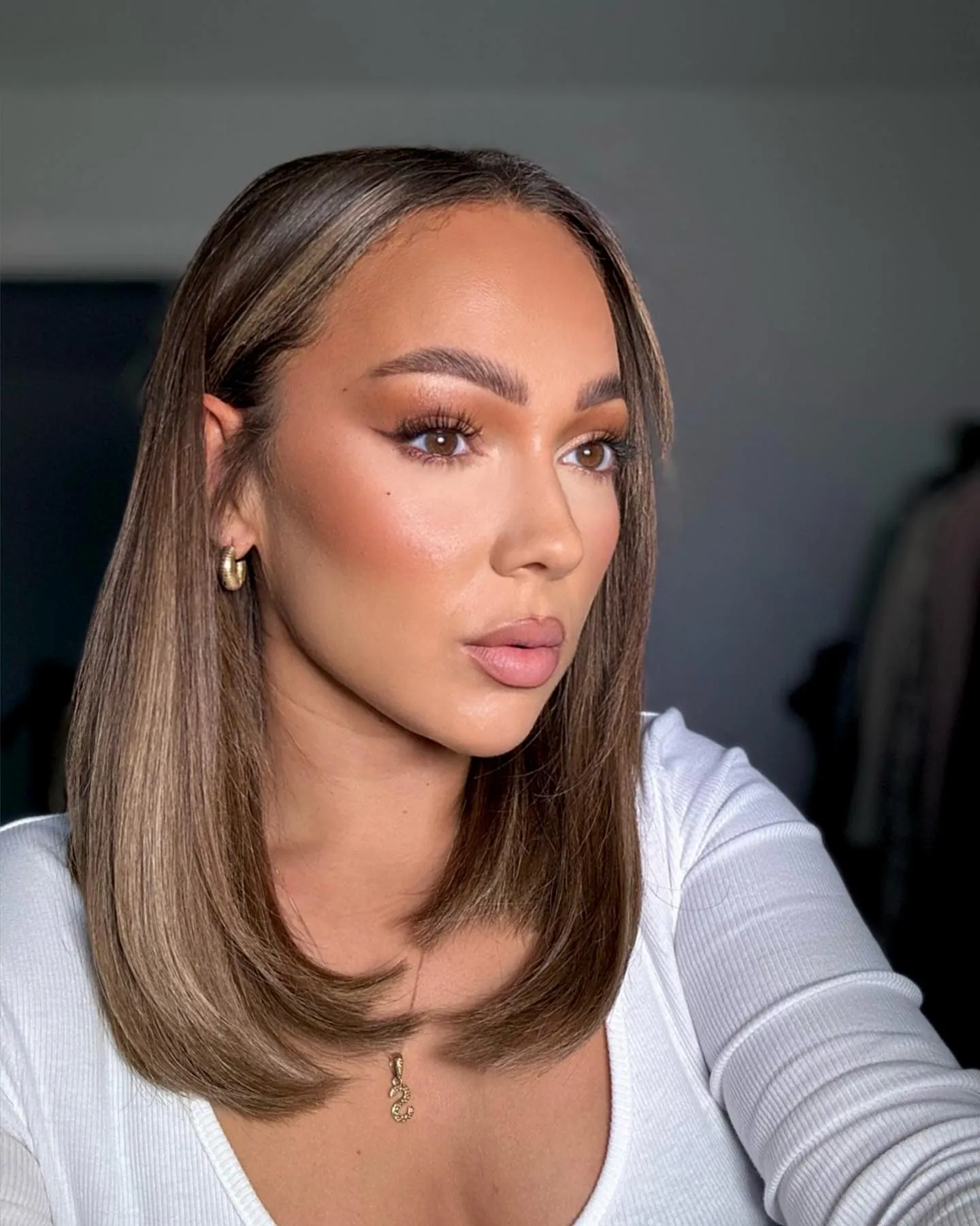Smooth light brown side-part long bob tucked behind one ear
