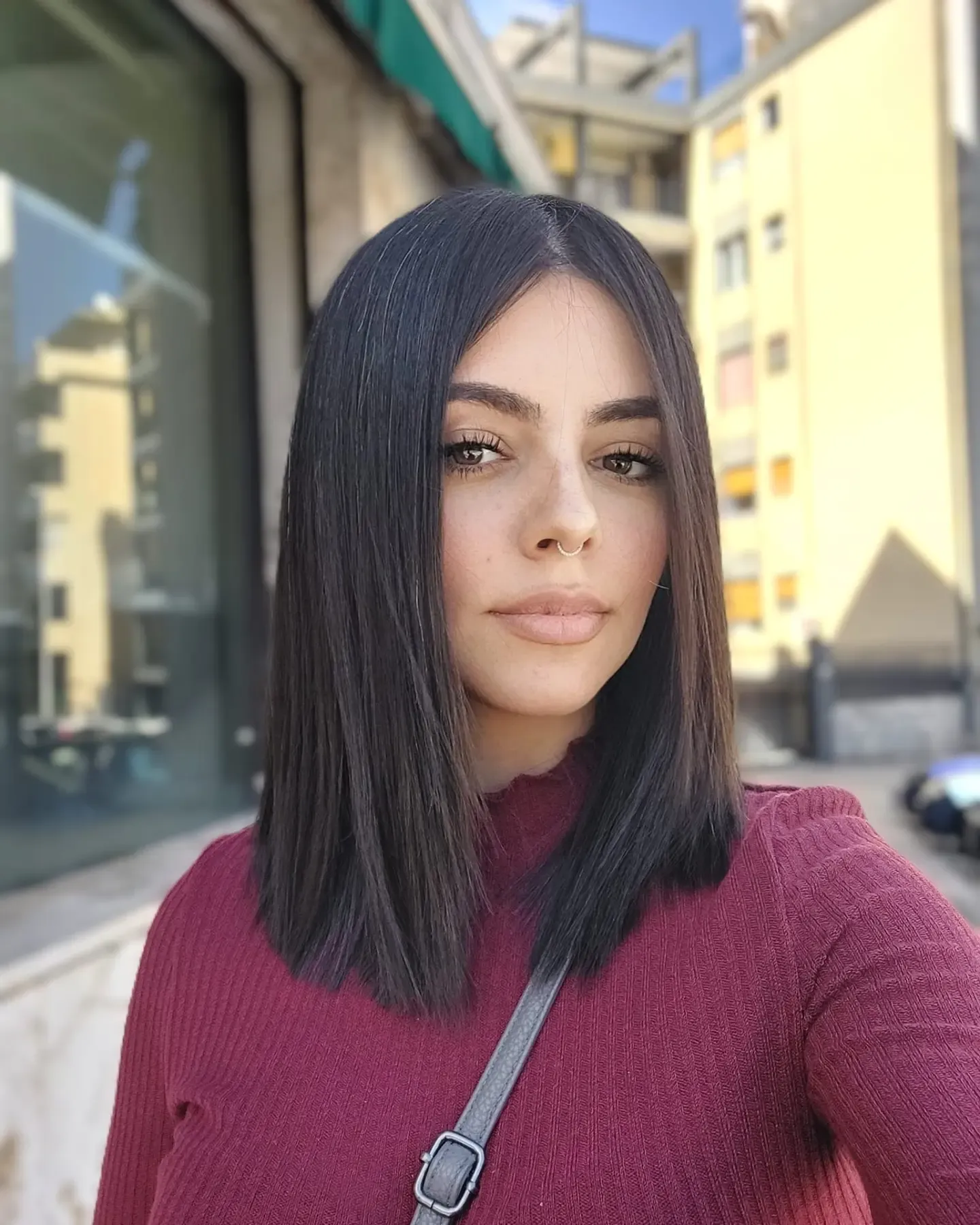 Dark sleek center-part long bob with straight blunt shoulder-length ends