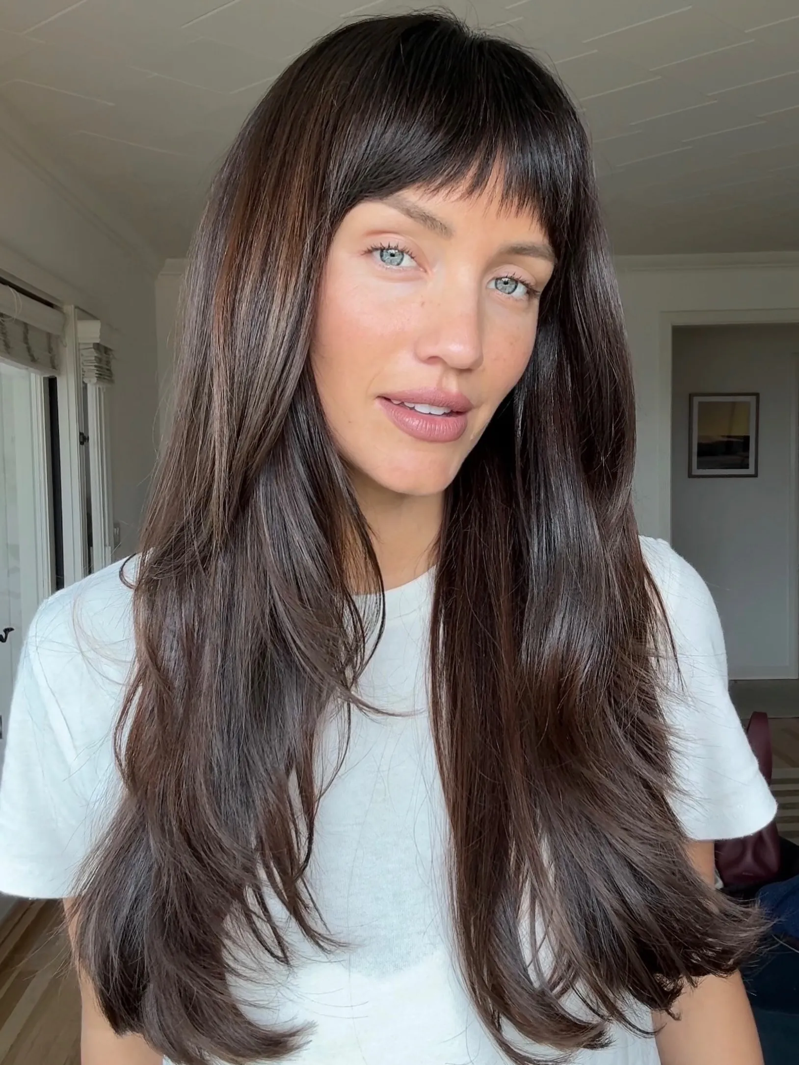 Long dark layered hair with a short micro fringe and flipped ends