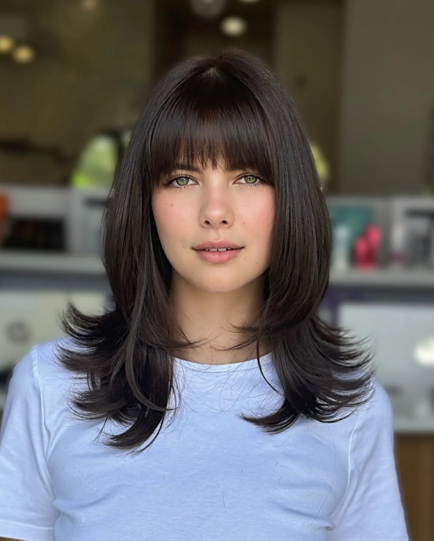 Dark medium-length layers with a full blunt fringe