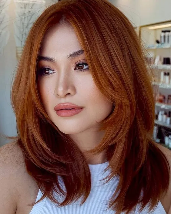 Copper medium-length hair with a side part and face-framing layers
