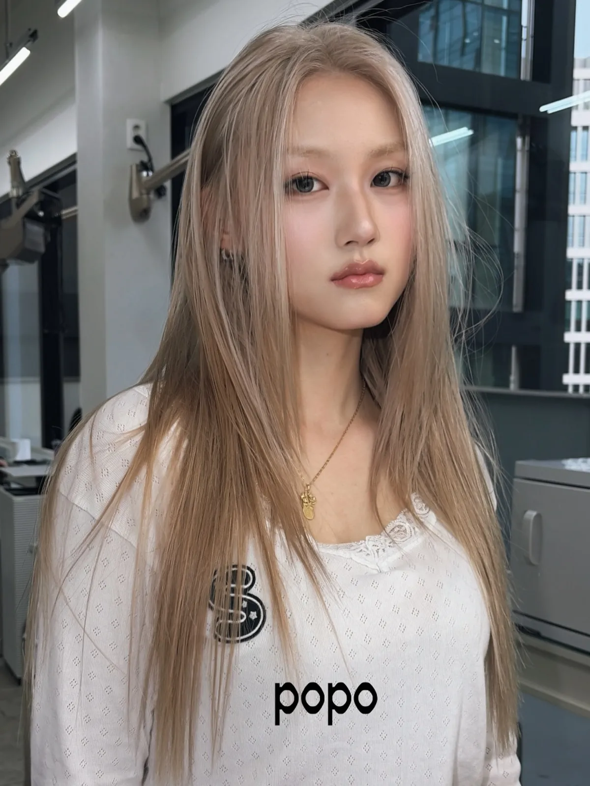 Long straight milk tea blonde hair with a center part and face-framing layers