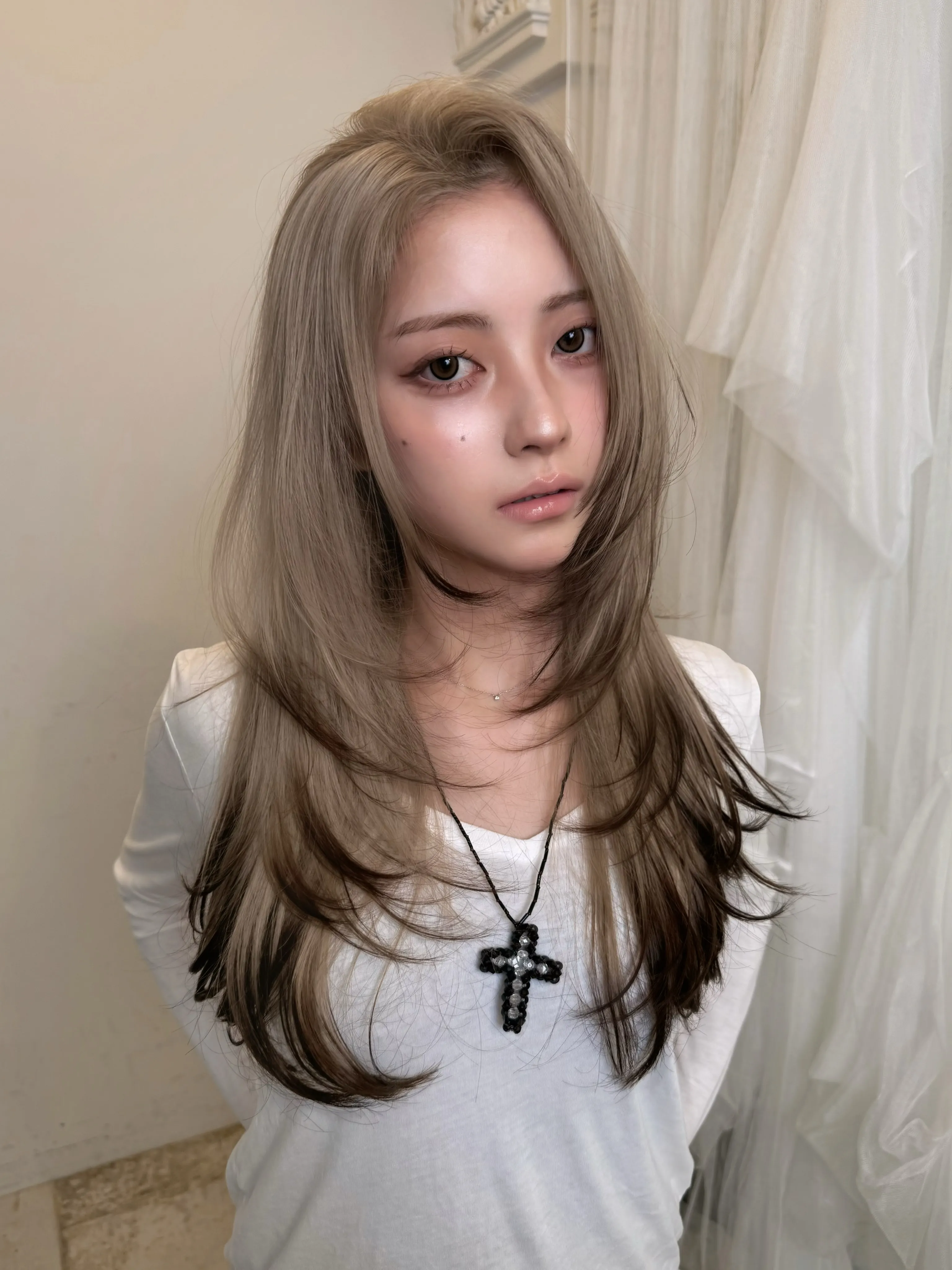 Long layered blonde hair with face-framing pieces and darker underneath tones