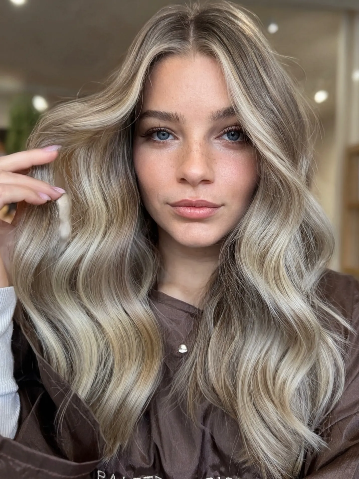 Long blonde waves with deeper roots and bright face-framing sections