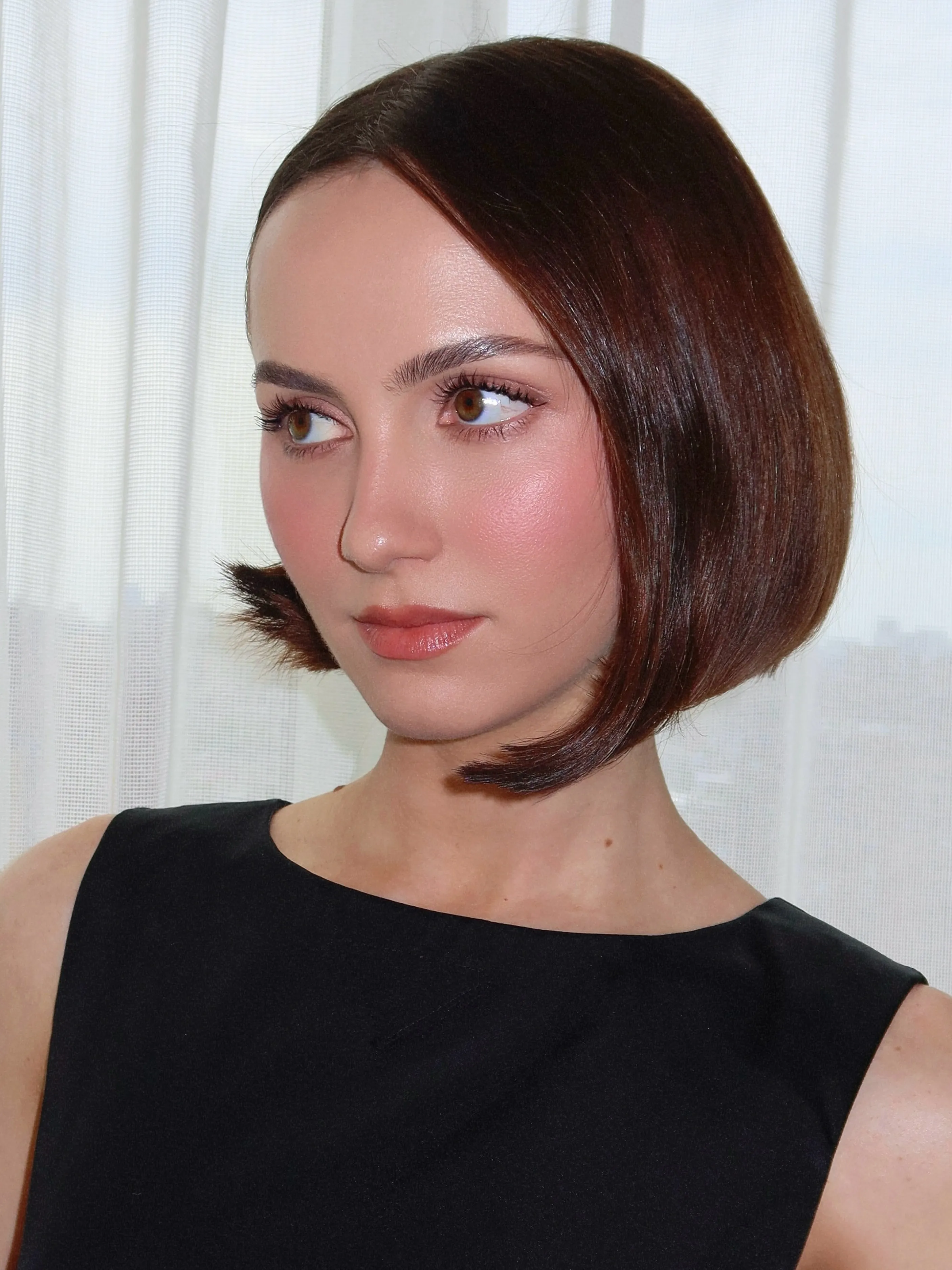 Sleek dark Prada bob with centre part and tucked ends