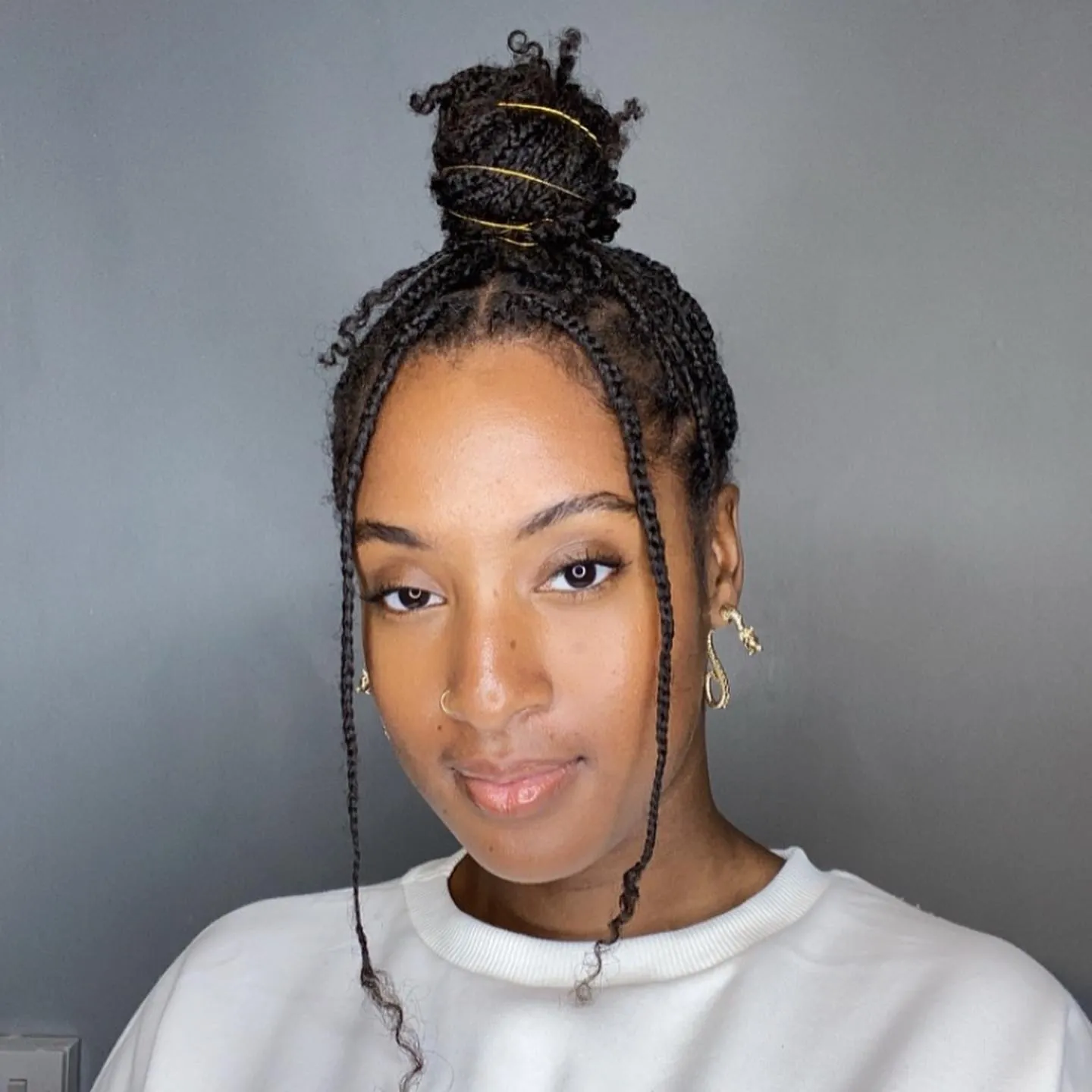 Mini braids gathered into a high top knot with two face pieces