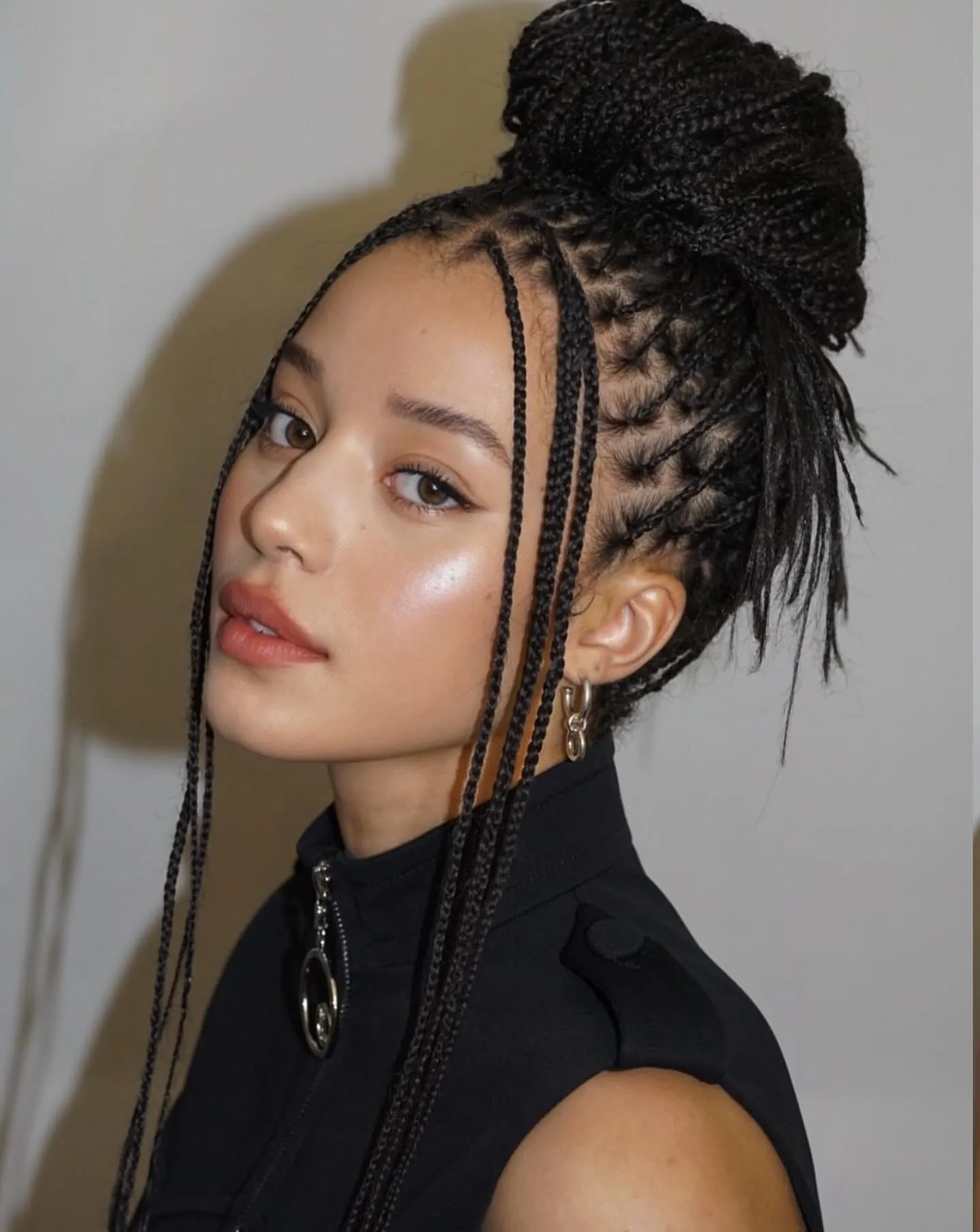 Long mini braids gathered into a high bun with face-framing braids