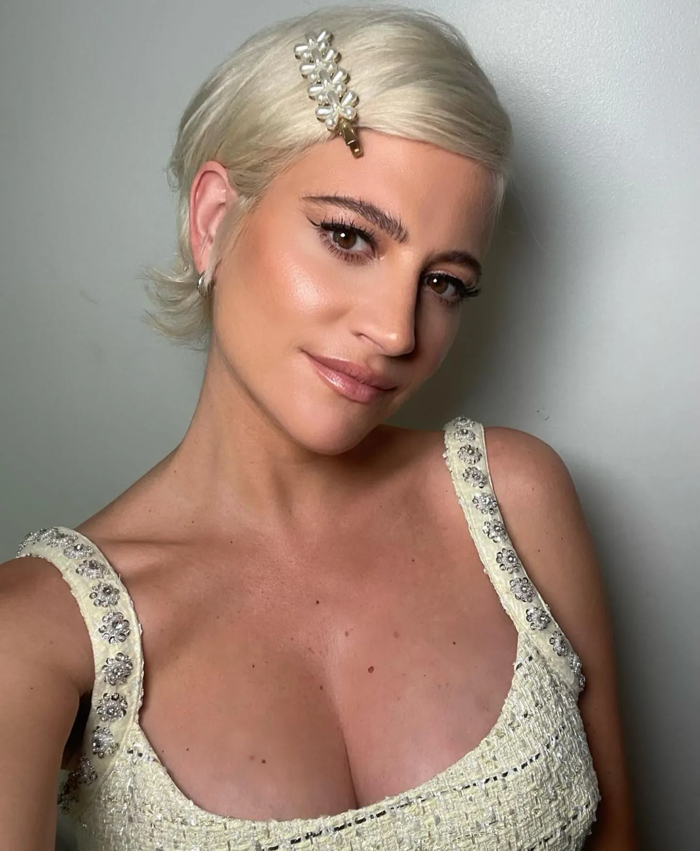 Platinum pixie slicked flat with decorative hair clip