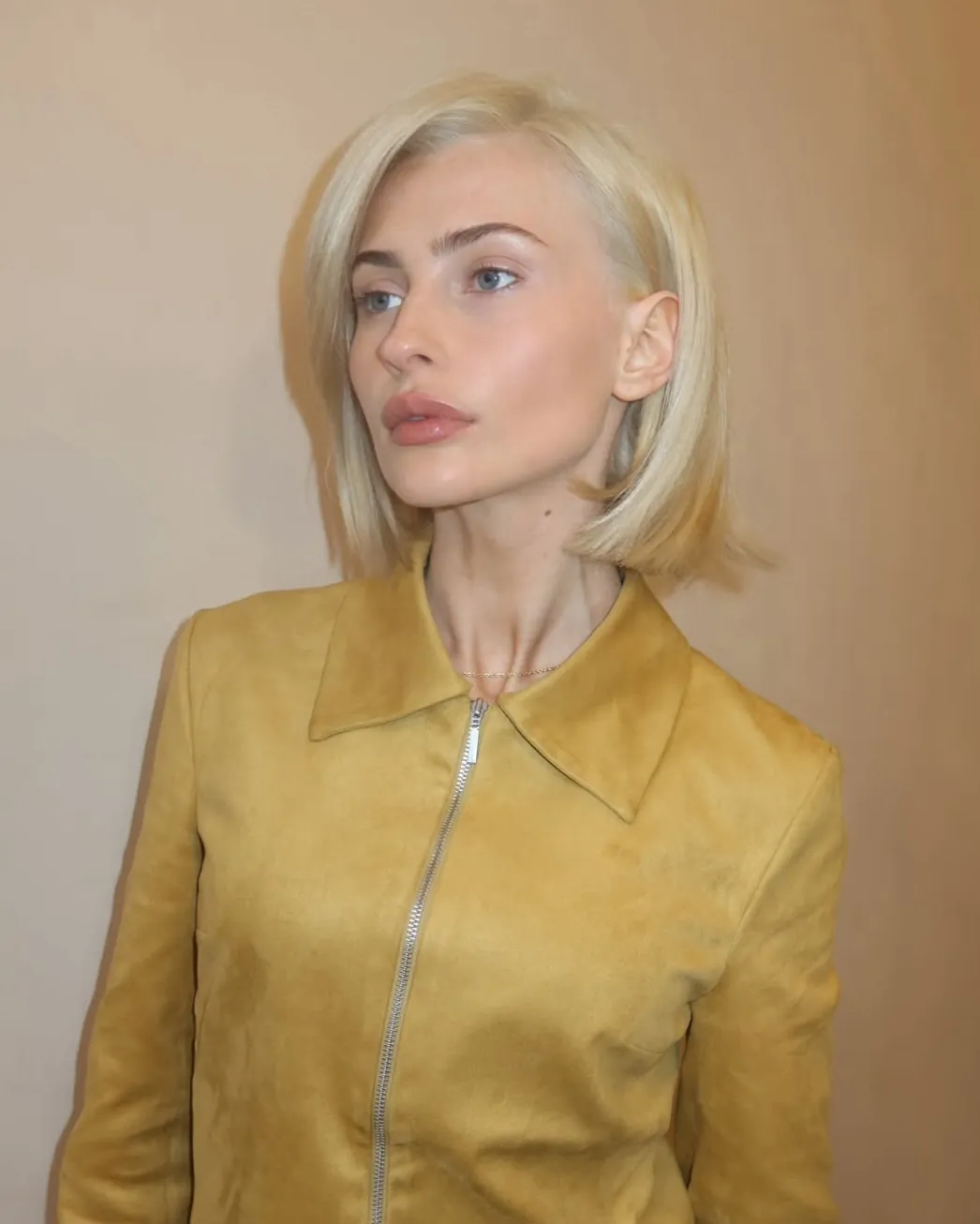Sleek suede blonde bob with side part and curved ends