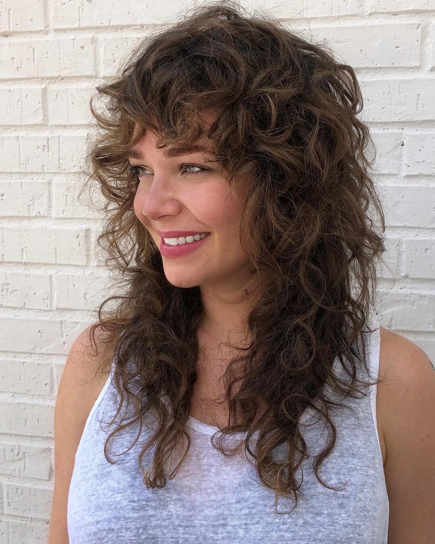 Long dark hair with full layered curls and short fringe
