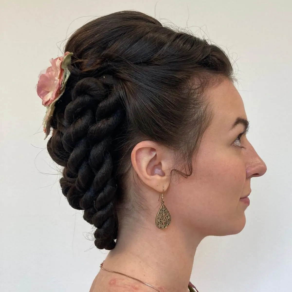 Dark braided Victorian updo with thick loops and flower accent