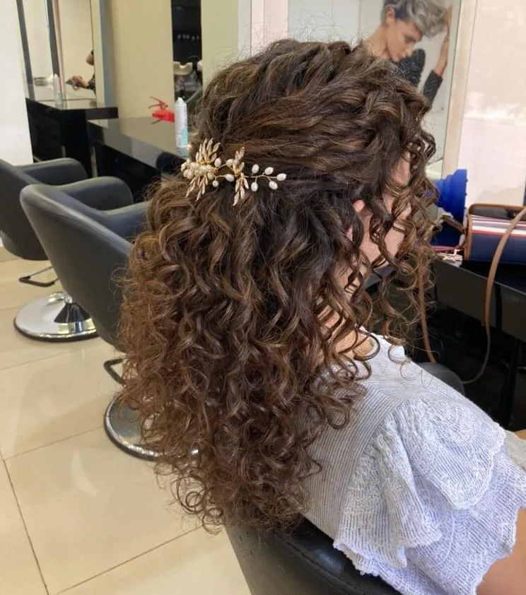 Half-up curly ponytail with a floral jeweled clip