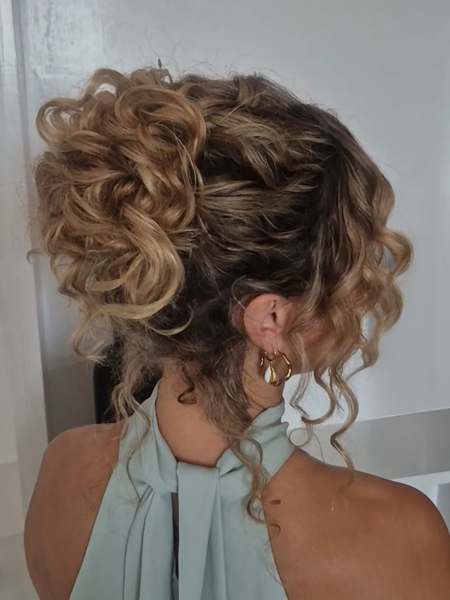 Voluminous curly updo with loose tendrils