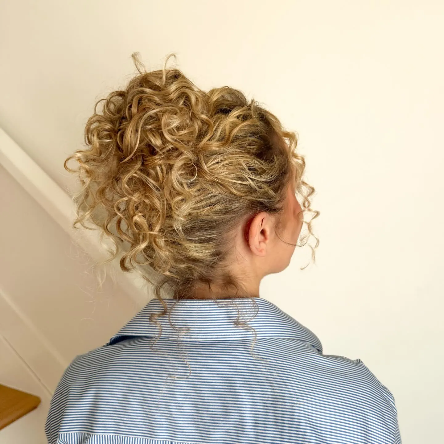 High curly bun with soft loose tendrils