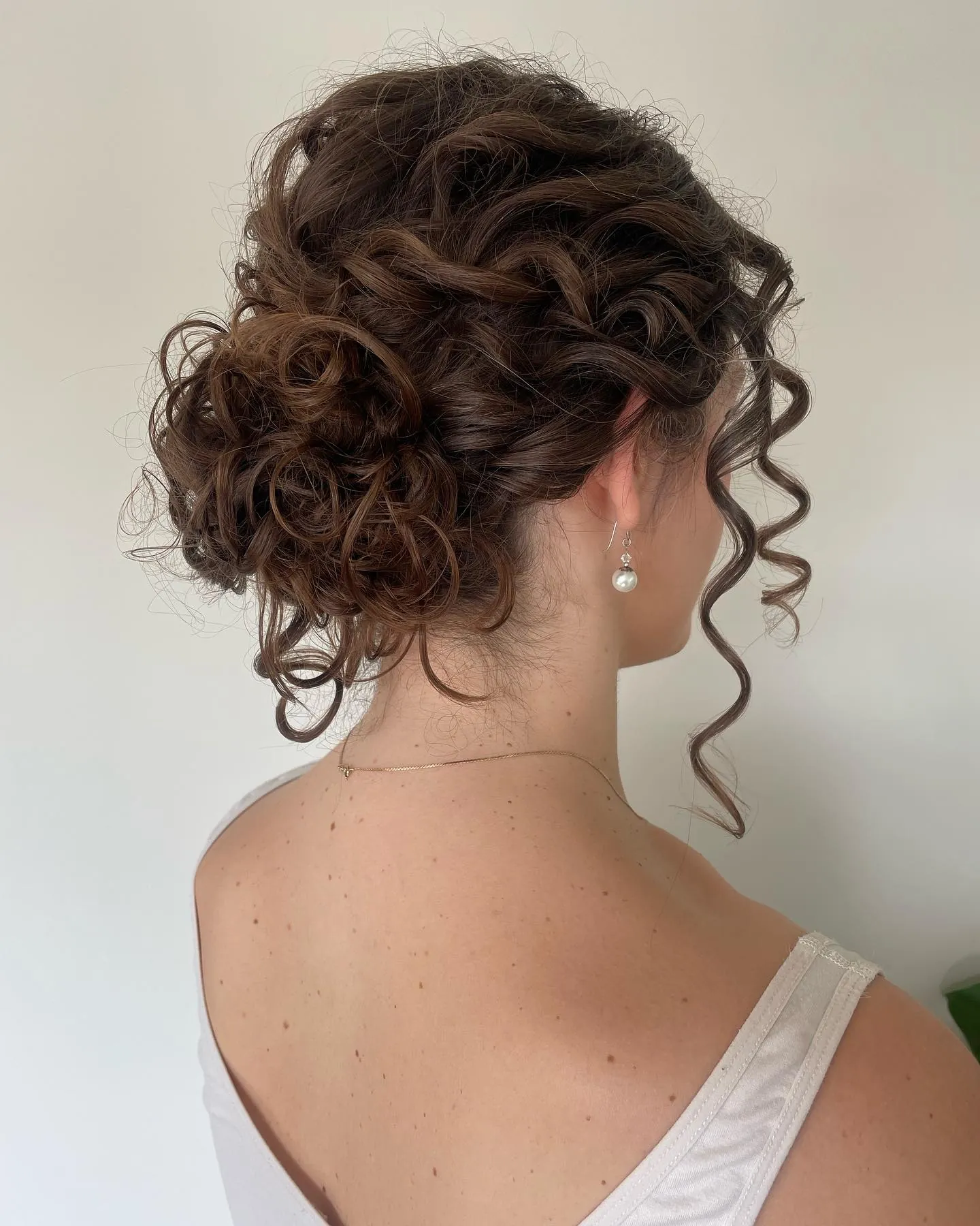 Low twisted curly updo with face-framing tendrils