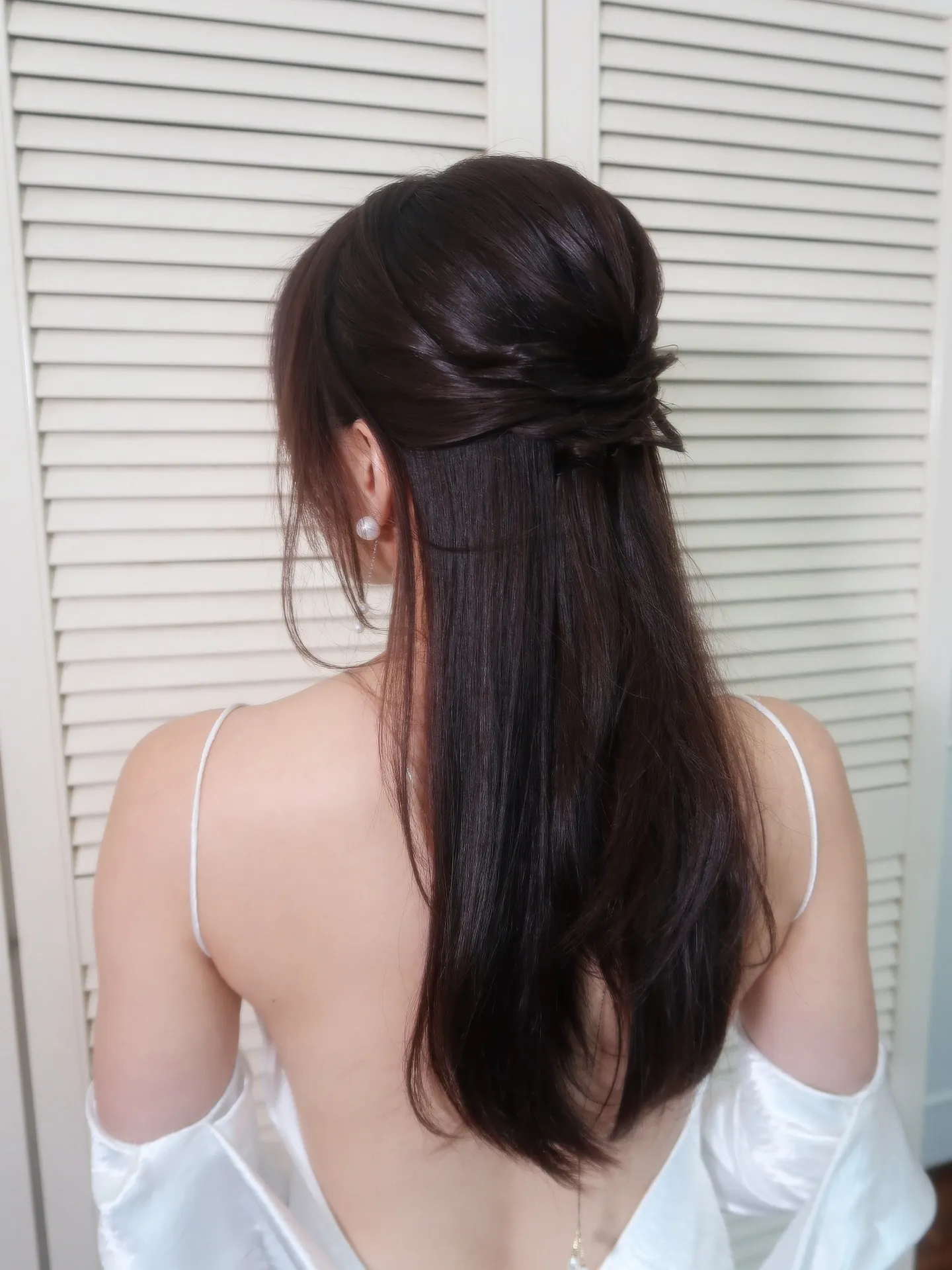 Long dark straight hair with a low twisted half-up style