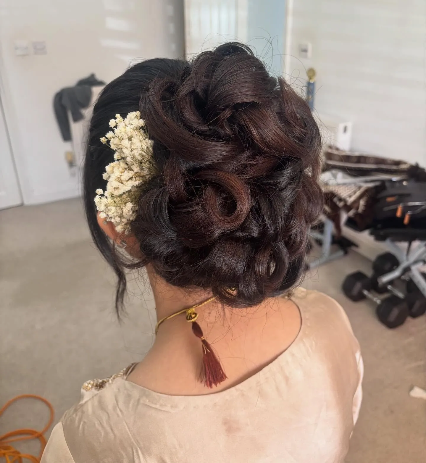 Full curled updo with sculpted loops and small white floral accents