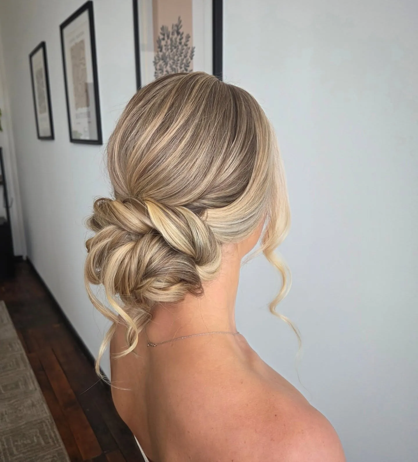 Blonde twisted low bun with loose face-framing tendrils