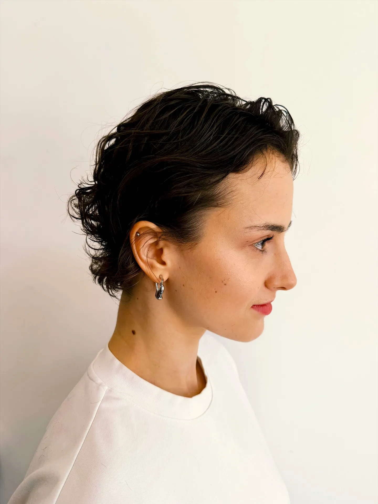 Curly pixie brushed back from the face