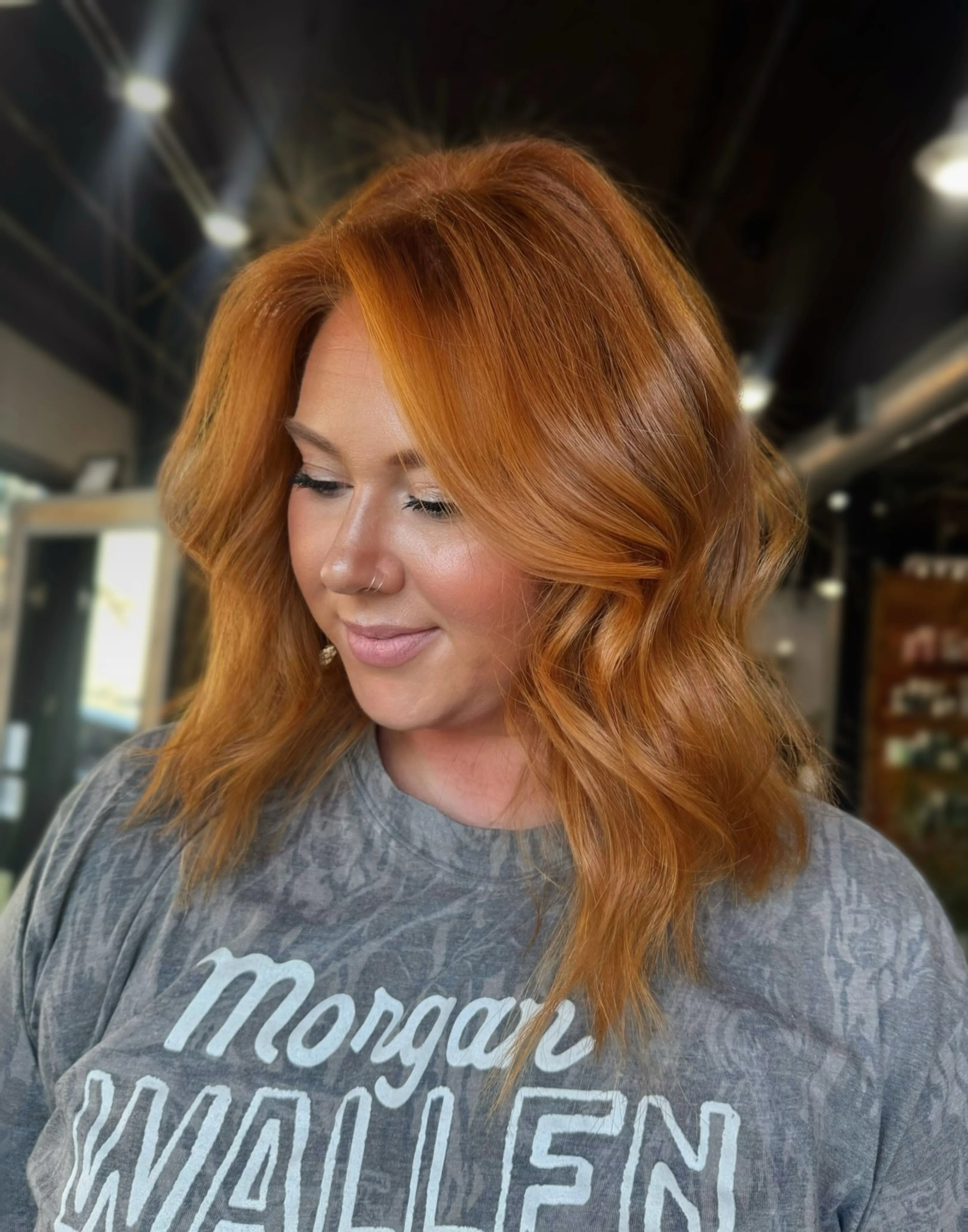 Shoulder-length bright copper hair with loose waves and a center part