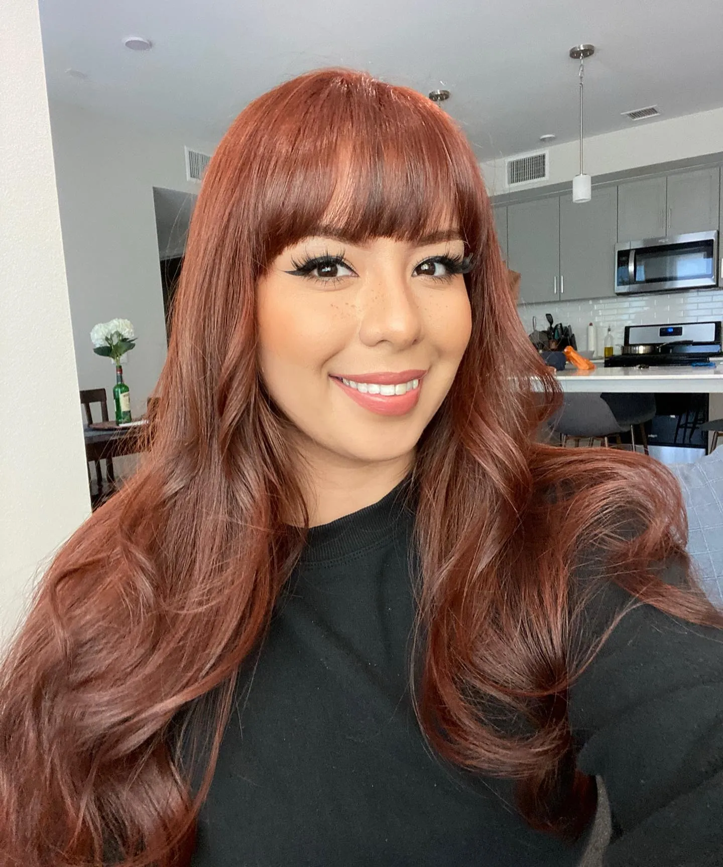 Long copper hair with a full straight fringe and softly curved layers