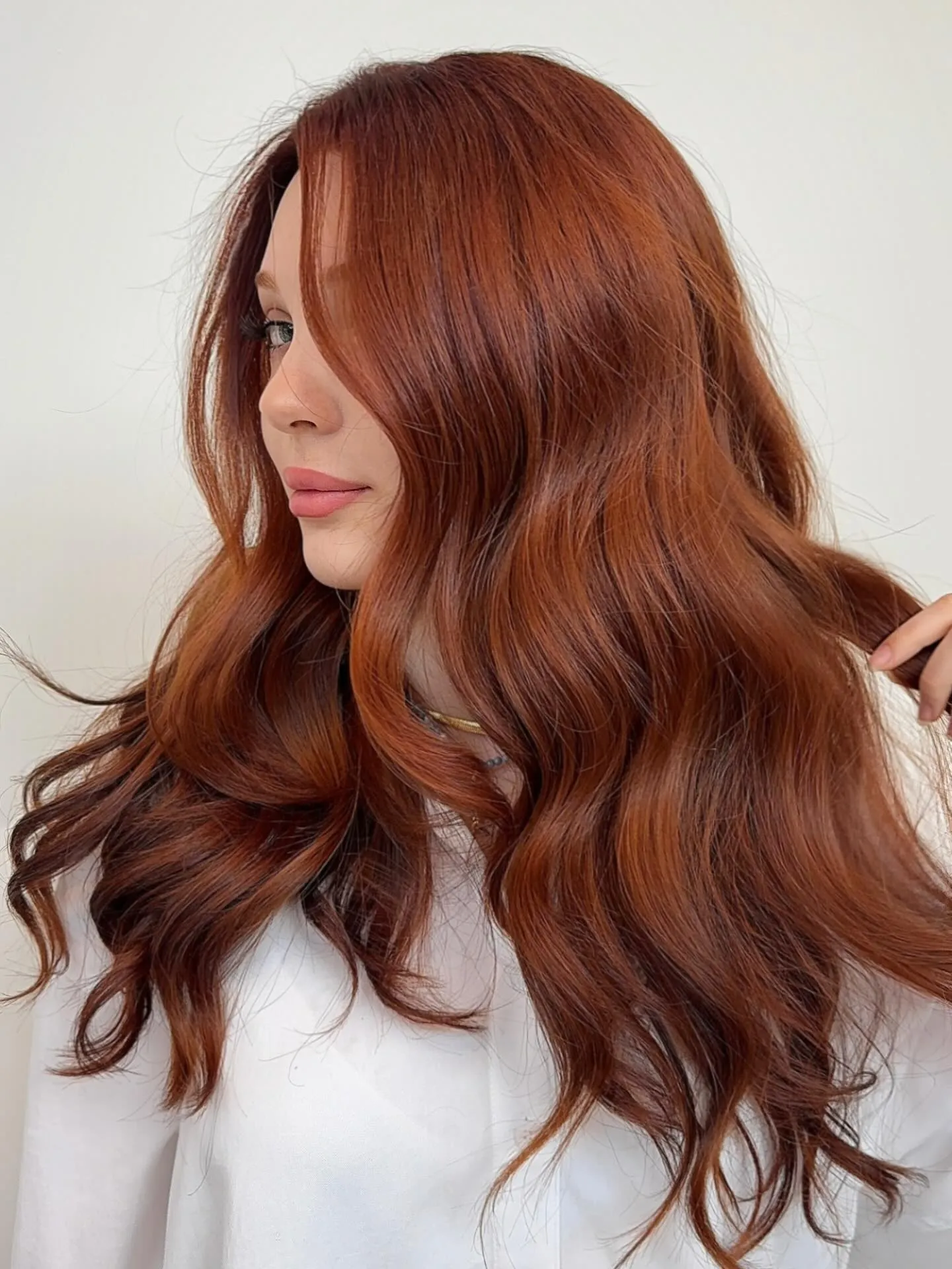 Long rich copper hair with a side part and flowing waves