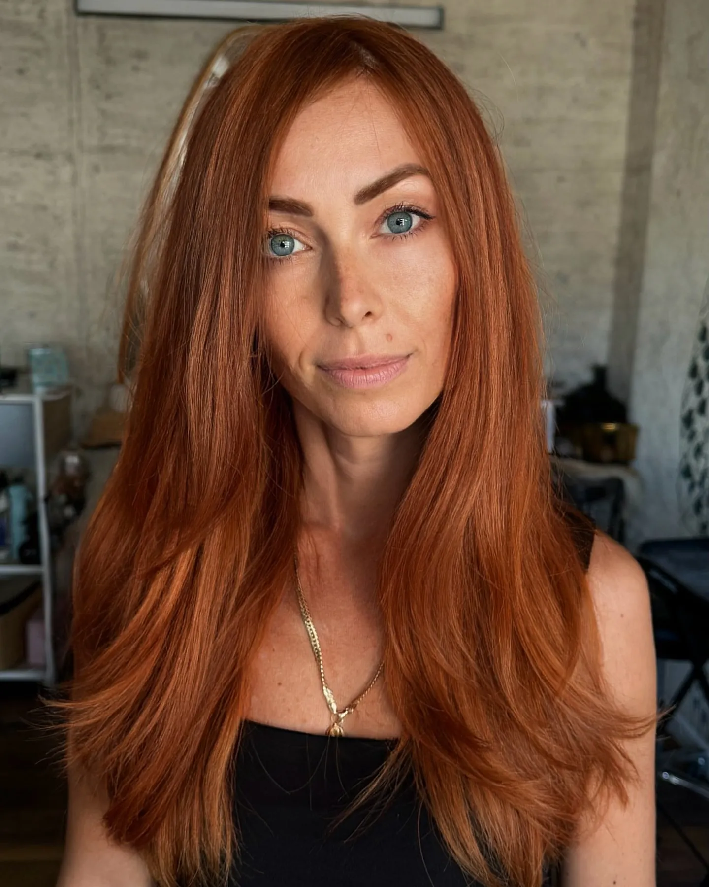 Long straight copper hair with subtle layers and a clean center part