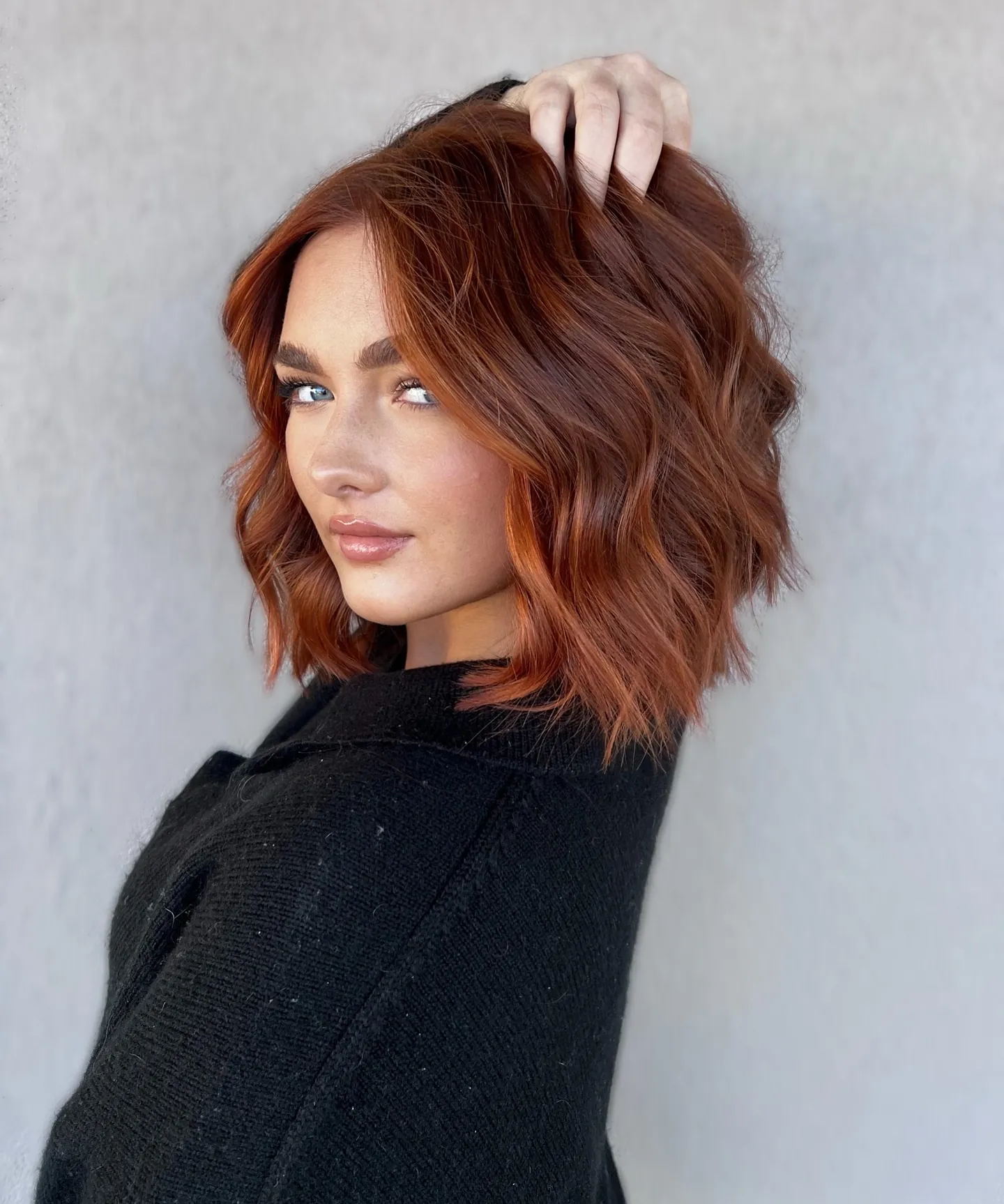 Short copper bob with loose tousled waves and a side part